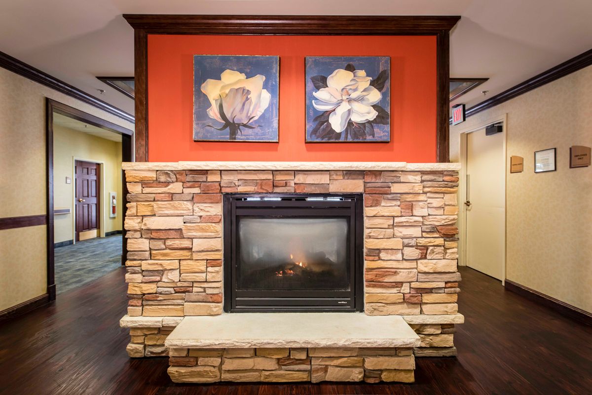A cozy stone fireplace with floral artwork on an orange accent wall.