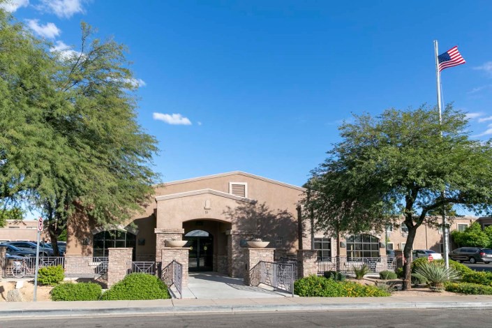 A brick building with an arched entrance surrounded by trees under a clear blue sky.