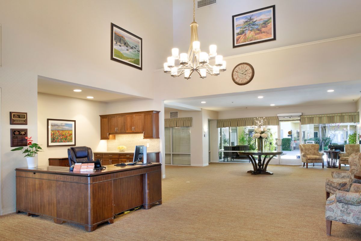 Elegant lobby with a chandelier, wooden desk, and artwork on the walls.