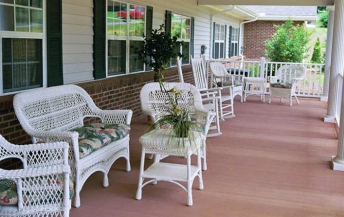 A cozy porch with wicker furniture and rocking chairs.