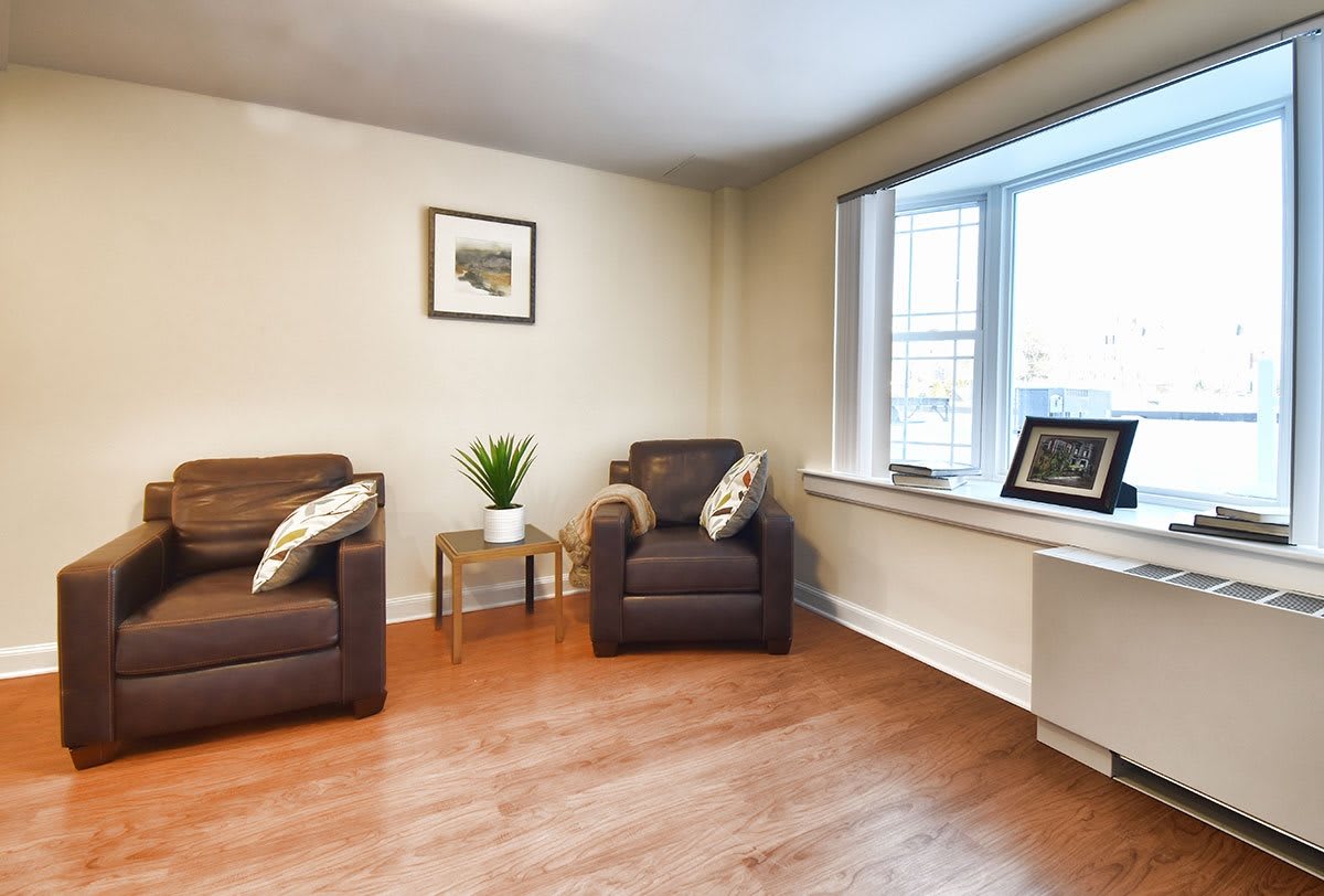 A cozy living room with two brown chairs and a side table near a large window.