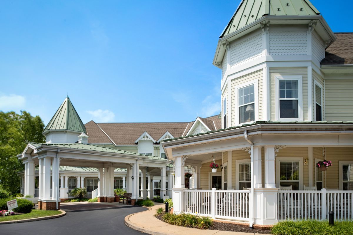 A large residential building with white exterior and gabled roofs under a clear blue sky.