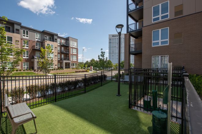 A modern urban apartment complex with green space and fenced outdoor areas.