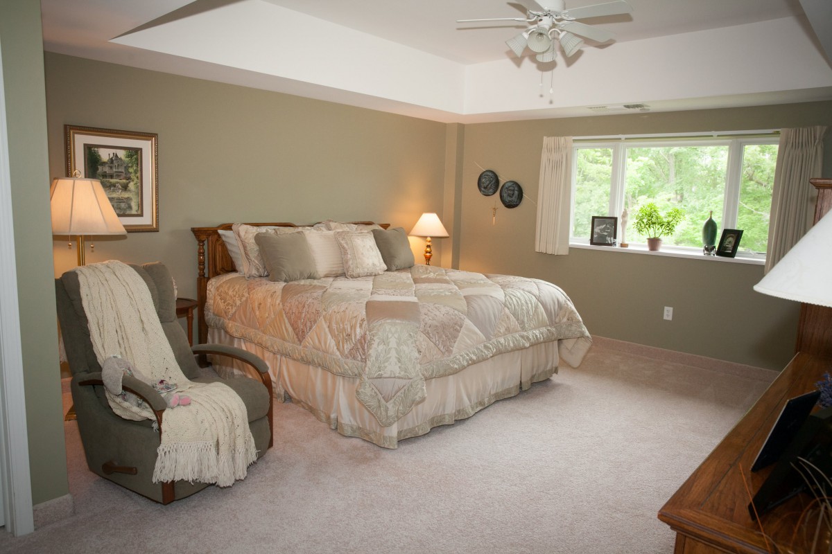 A cozy bedroom with a large bed, soft lighting, and a window letting in natural light.