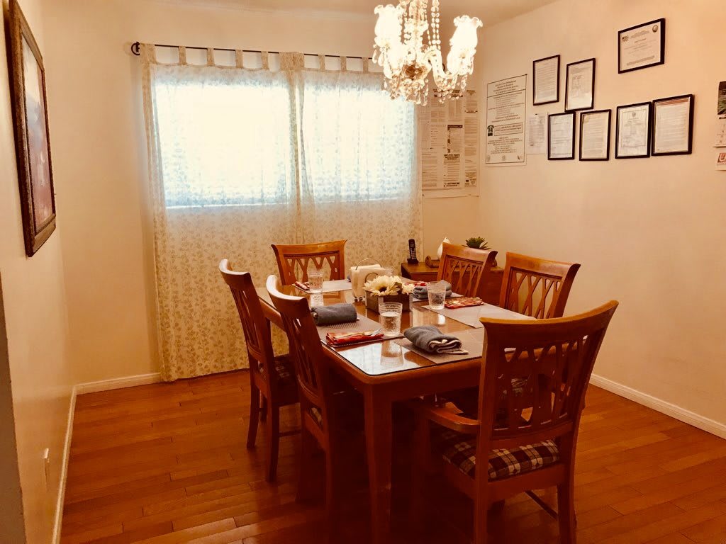 A cozy dining room with a wooden table, chairs, and a chandelier.