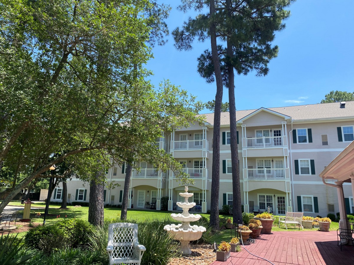 A scenic view of a residential building with a fountain and a well-maintained garden.