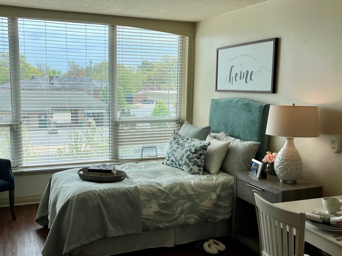 A cozy bedroom with a neatly made bed, large window, and stylish decor.