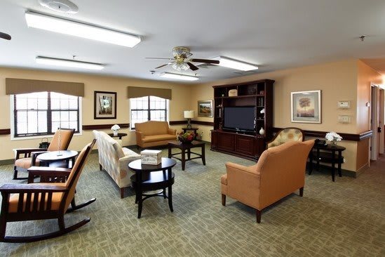 A cozy living room with comfortable seating, a TV, and a bookshelf.