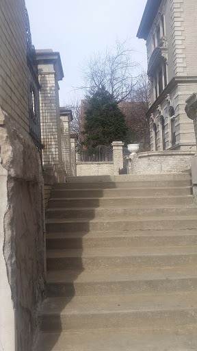 A view of stone steps leading up, flanked by a classic architectural structure.