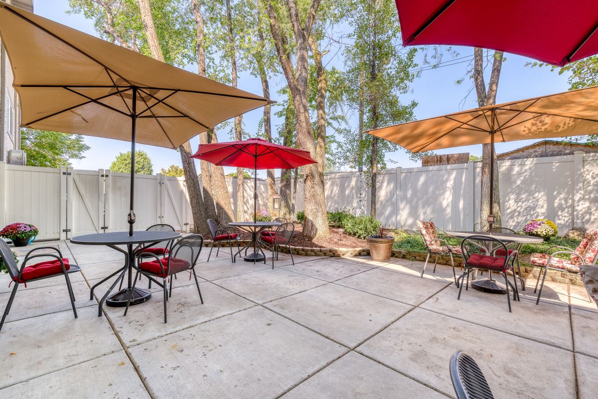 A sunny outdoor patio with tables and umbrellas providing shade.