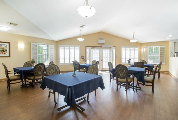 A spacious dining area with tables and chairs, illuminated by natural light from large windows.
