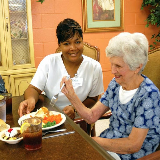 A caregiver assists an elderly woman during a meal, highlighting the importance of companionship in senior care.