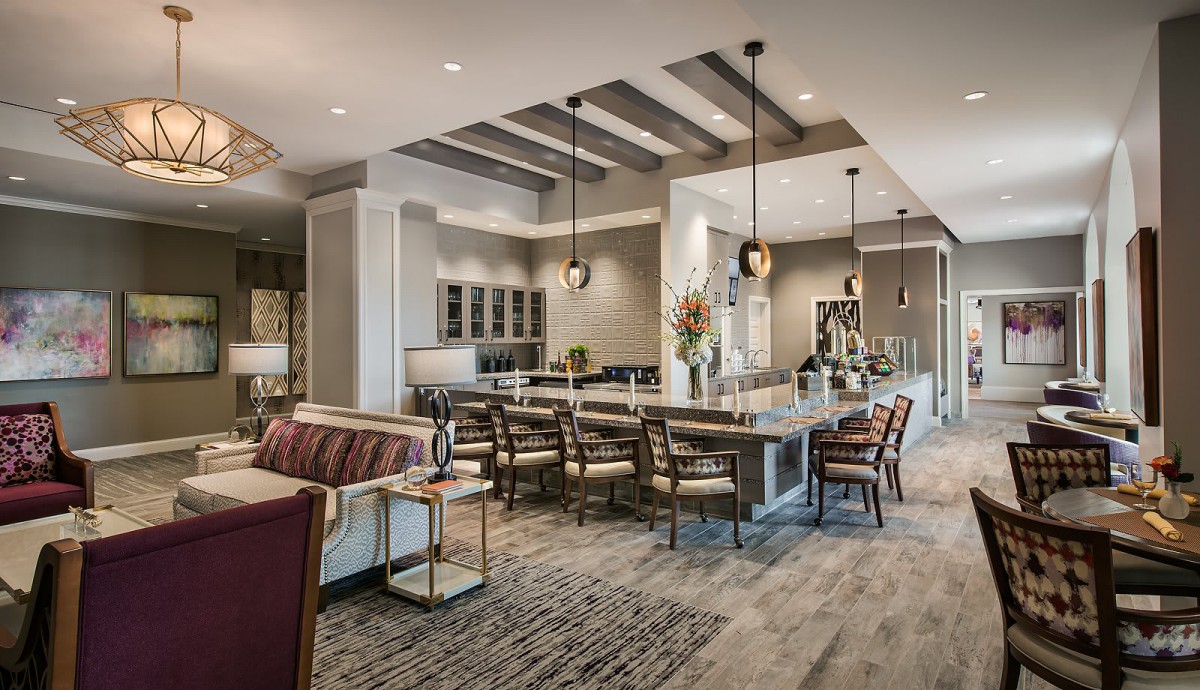 A spacious and modern kitchen with an open layout, featuring a large island, bar stools, and elegant pendant lights.