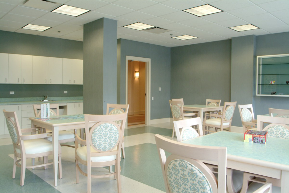 An empty dining area with modern furniture and a kitchenette.