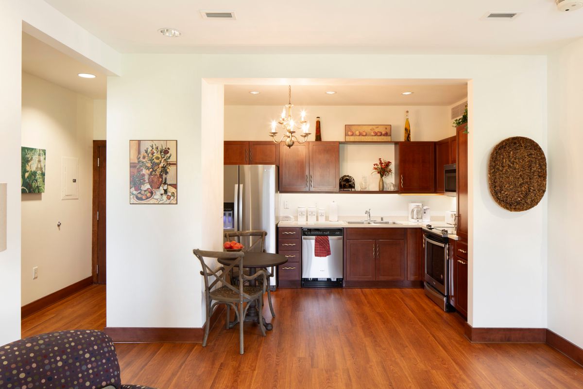 A modern kitchen with wood flooring, stainless steel appliances, and a cozy dining area.