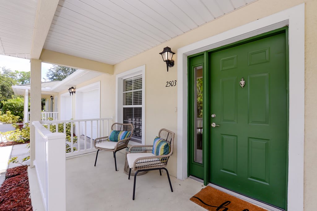 A cozy porch with a green door and outdoor seating.