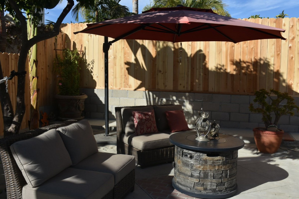 A cozy outdoor patio with seating and a fire pit under an umbrella.
