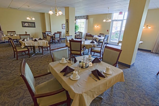 A neatly arranged dining room with several tables and chairs, set for service.