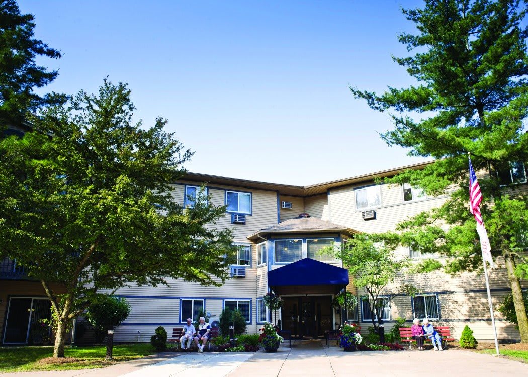 A residential apartment building with a main entrance and surrounding greenery.
