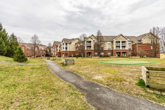 An apartment complex with a central pathway and surrounding grassy areas, under an overcast sky.