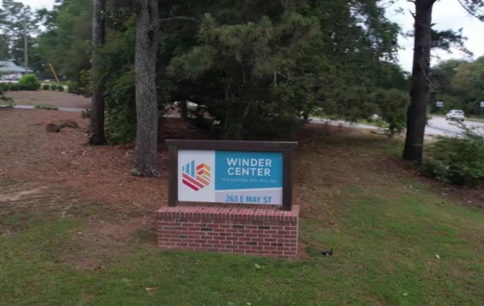 An outdoor sign for a center surrounded by trees.