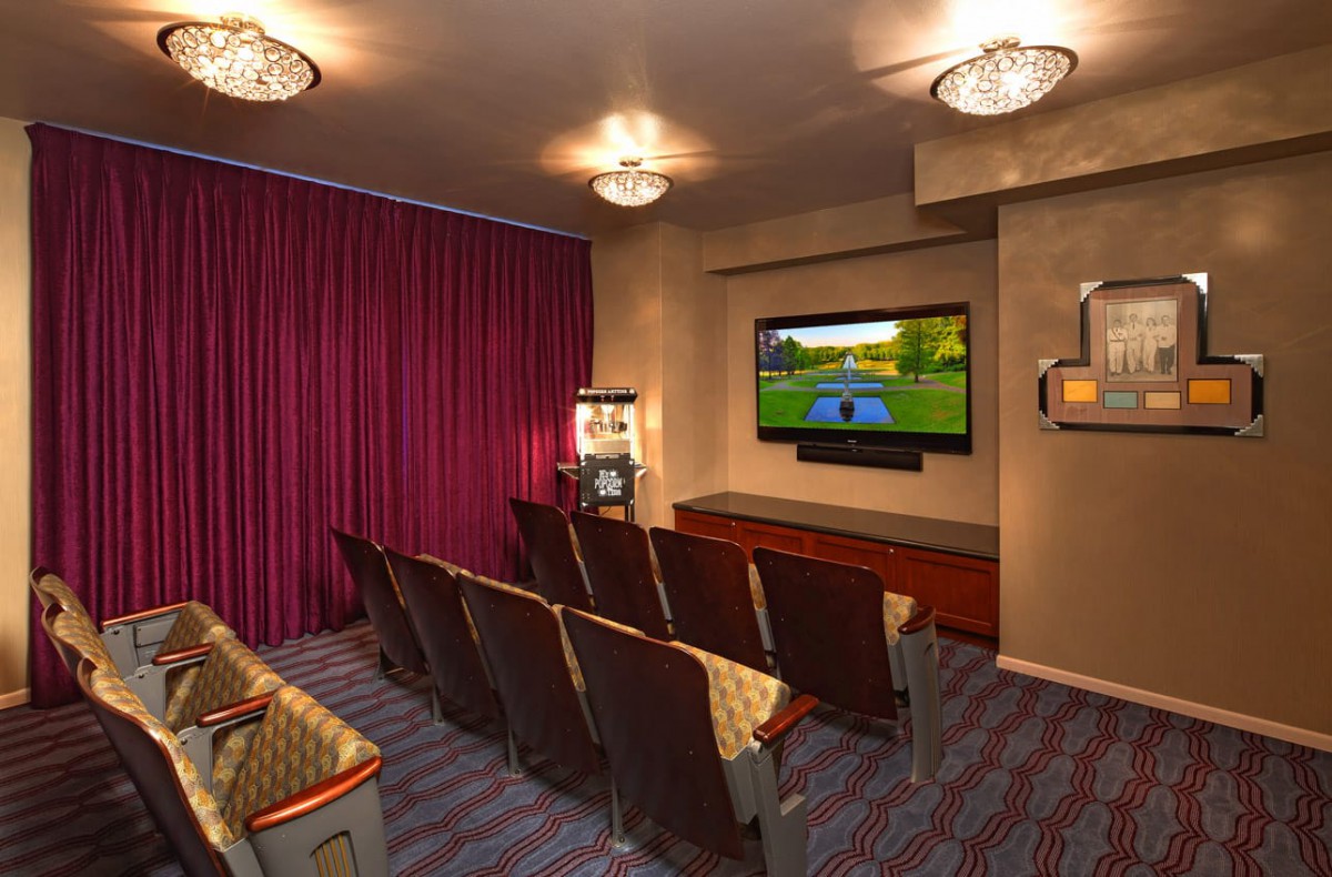 A cozy home theater with rows of seating facing a large TV screen.
