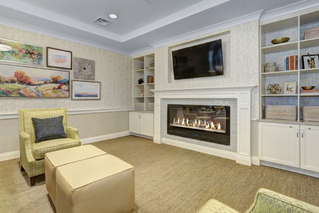 A cozy living room with a modern fireplace, a wall-mounted TV, and comfortable seating.