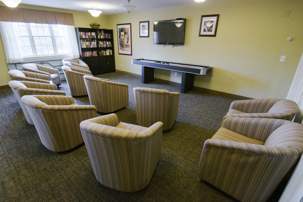 A cozy lounge area with striped chairs facing a television and bookshelf.