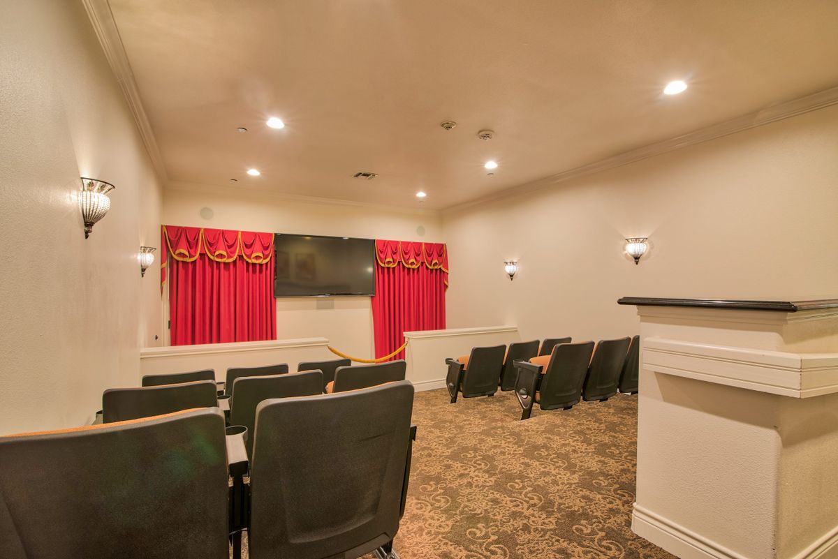 A cozy home theater with comfortable seating, red curtains, and a large screen.