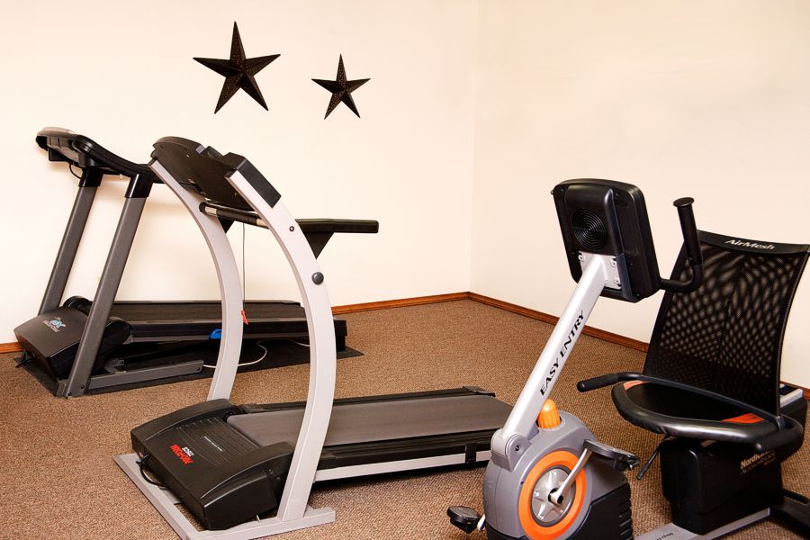 A small workout room with a treadmill and an exercise bike, decorated with star accents on the wall.