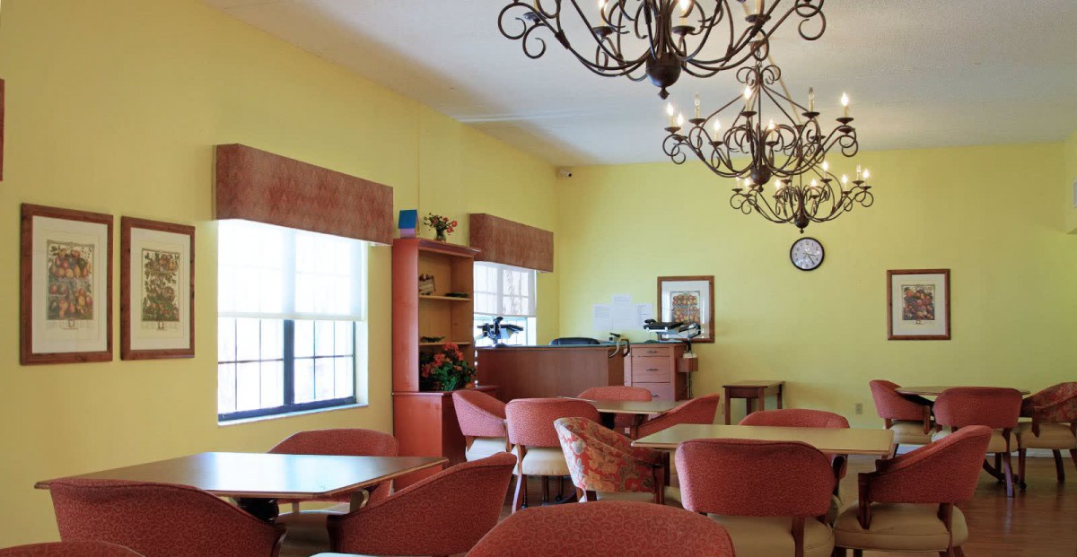 An empty cafe interior with tables and chairs, adorned with chandeliers.