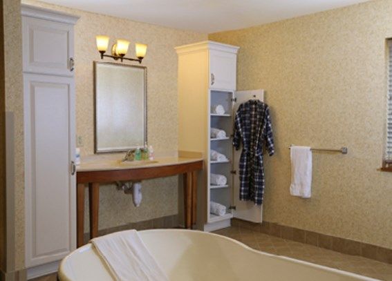 A stylish bathroom with a mirror, sink, robe on a wall hook, and neatly arranged shelves.