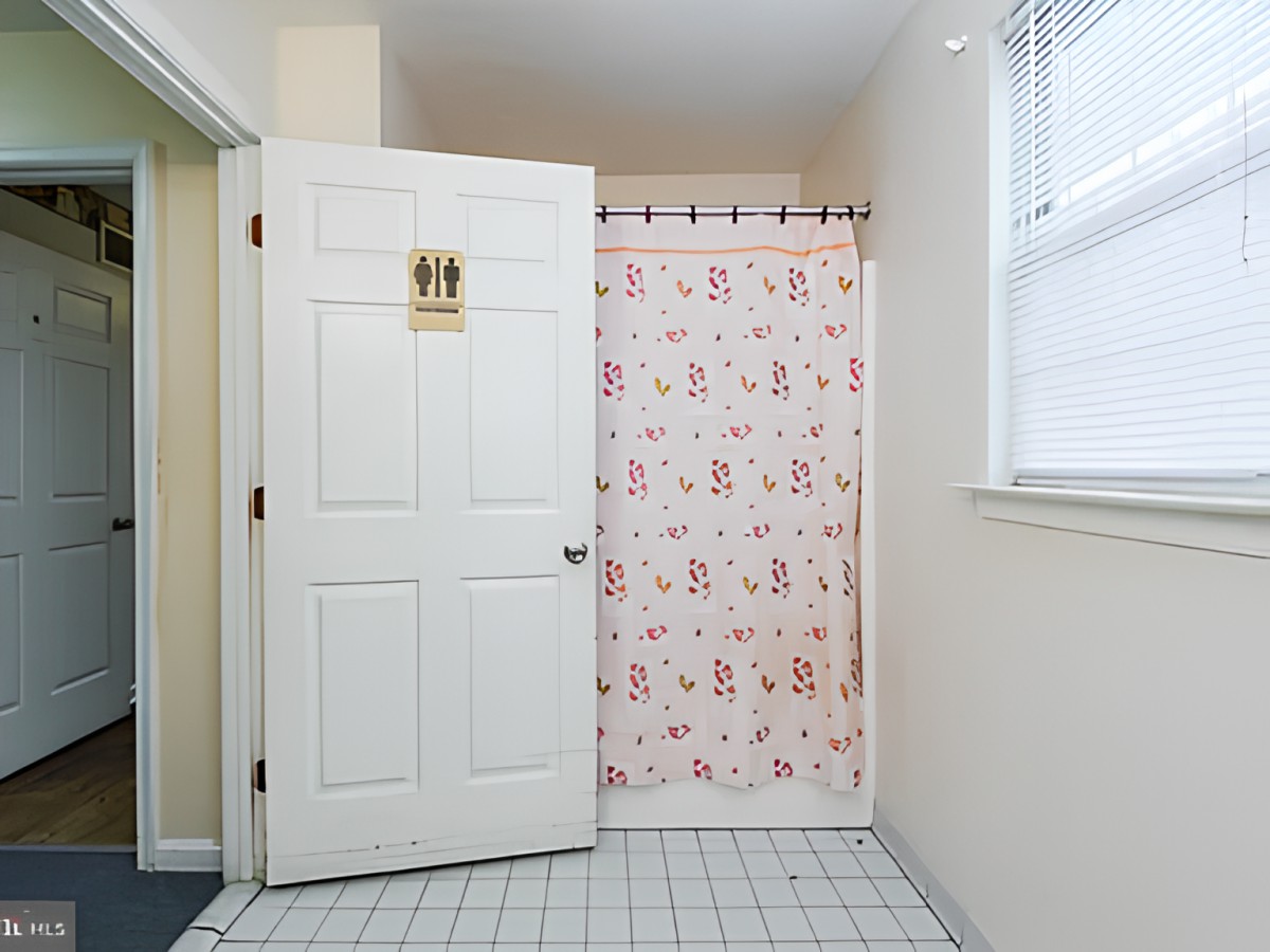 A bathroom with a patterned shower curtain and white tiled floor.