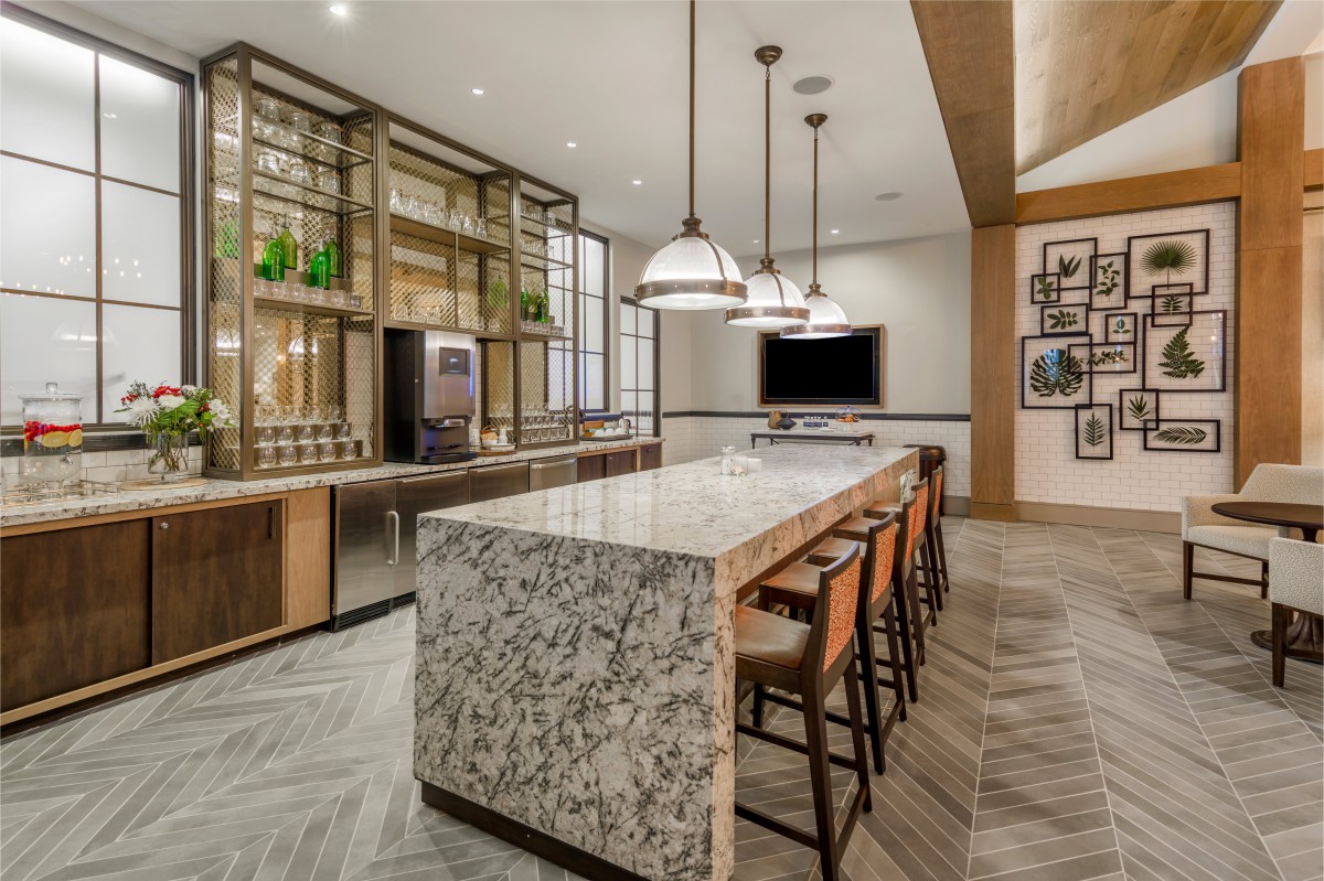 A modern kitchen with a large island countertop and stylish bar stools, illuminated by elegant pendant lights.