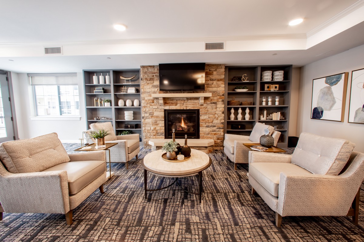 A modern and cozy living room featuring a stone fireplace, comfortable seating, and built-in bookshelves.
