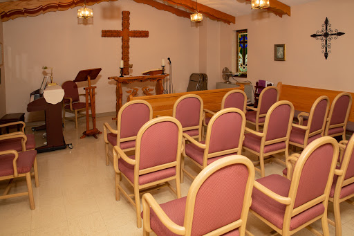 A serene interior view of a church with seating and a wooden cross.