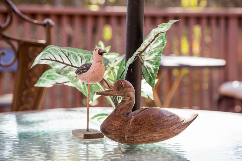 Wooden bird sculptures on an outdoor table with leaf decorations.