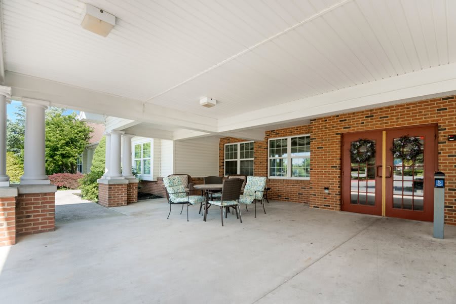 A spacious covered patio with a brick wall, featuring a table and chairs set in a cozy outdoor seating arrangement.