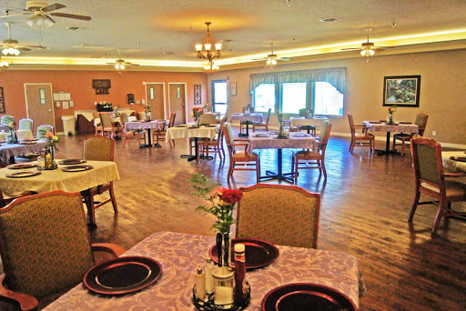 A cozy dining area with neatly arranged tables and chairs, featuring floral centerpieces.