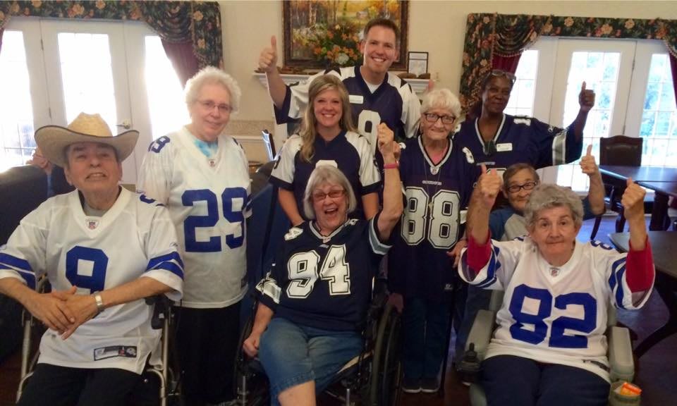 A cheerful group of people wearing sports jerseys, celebrating together indoors.