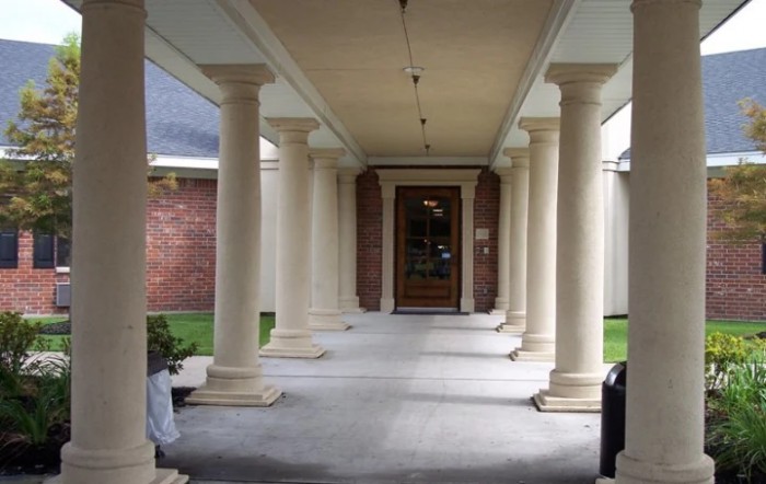 A grand entrance with rows of columns leading to a wooden door.