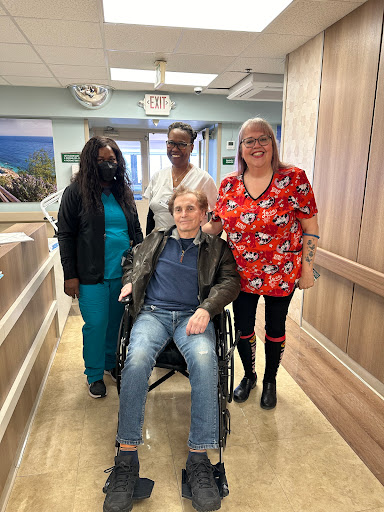A group of caregivers and a patient share a moment in a healthcare facility.