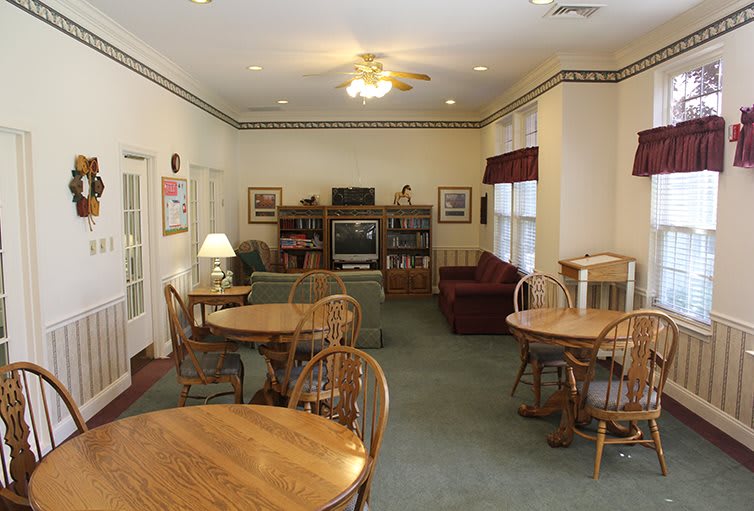 A cozy living room with wooden tables, chairs, a sofa, and a television.