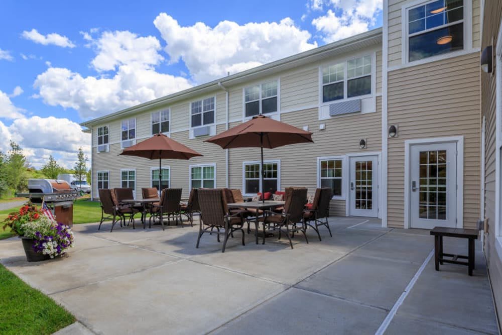 Outdoor patio area with tables and umbrellas in front of a building.
