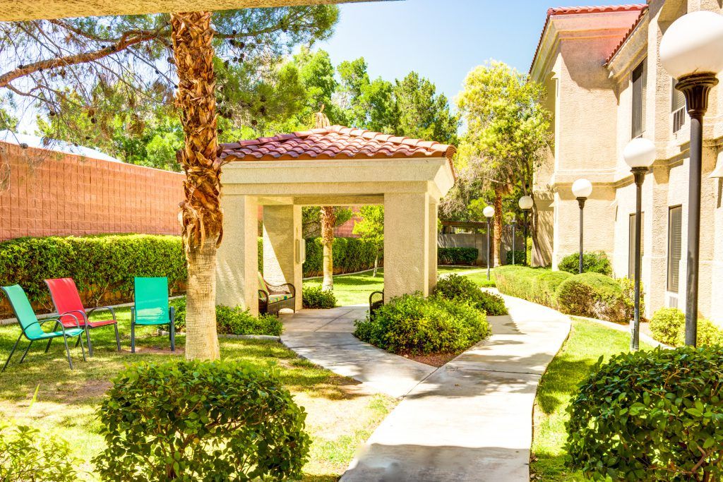 A sunny garden with a gazebo and winding pathways surrounded by lush greenery.