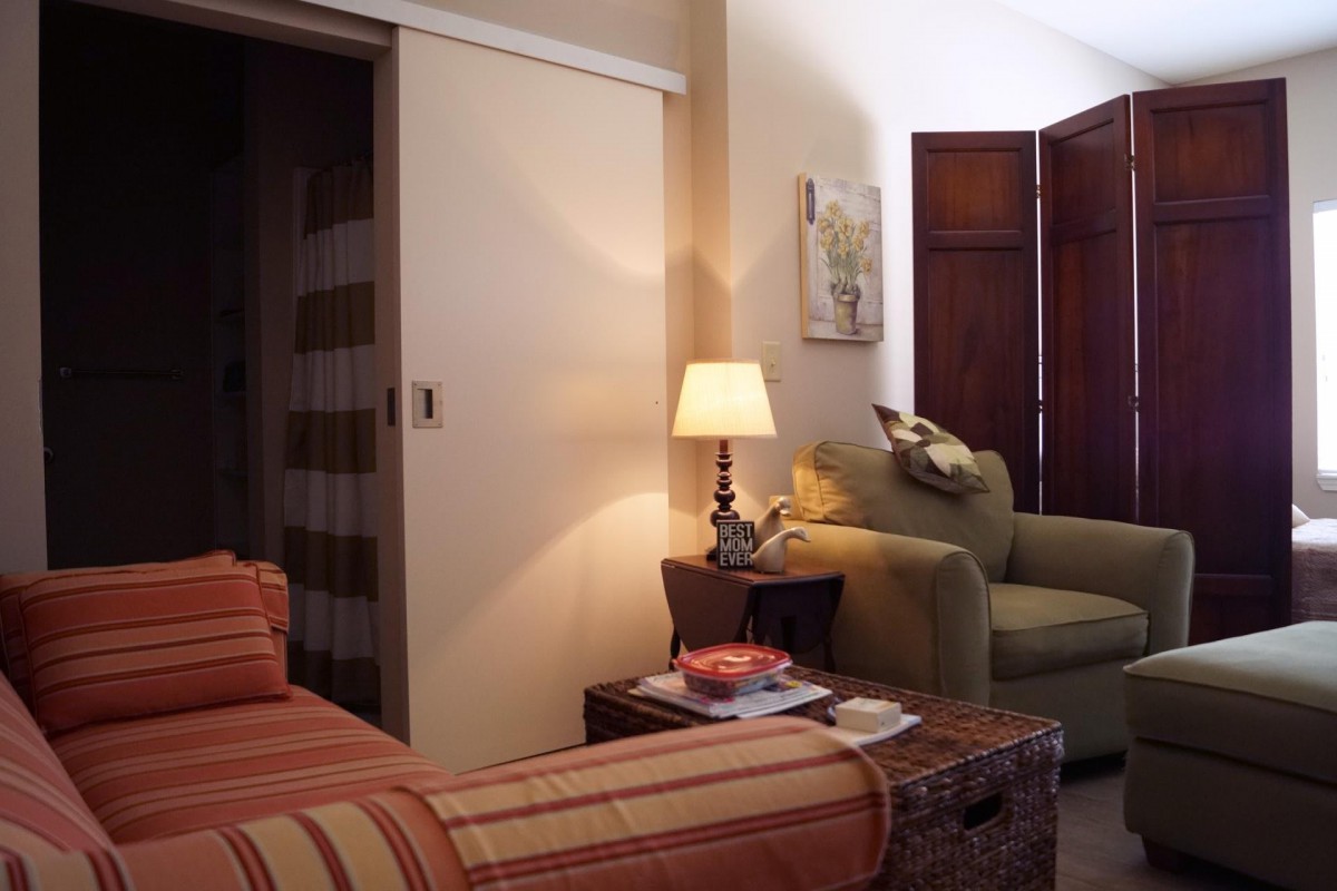 A cozy bedroom with a bed, armchair, and a lamp illuminating the space.