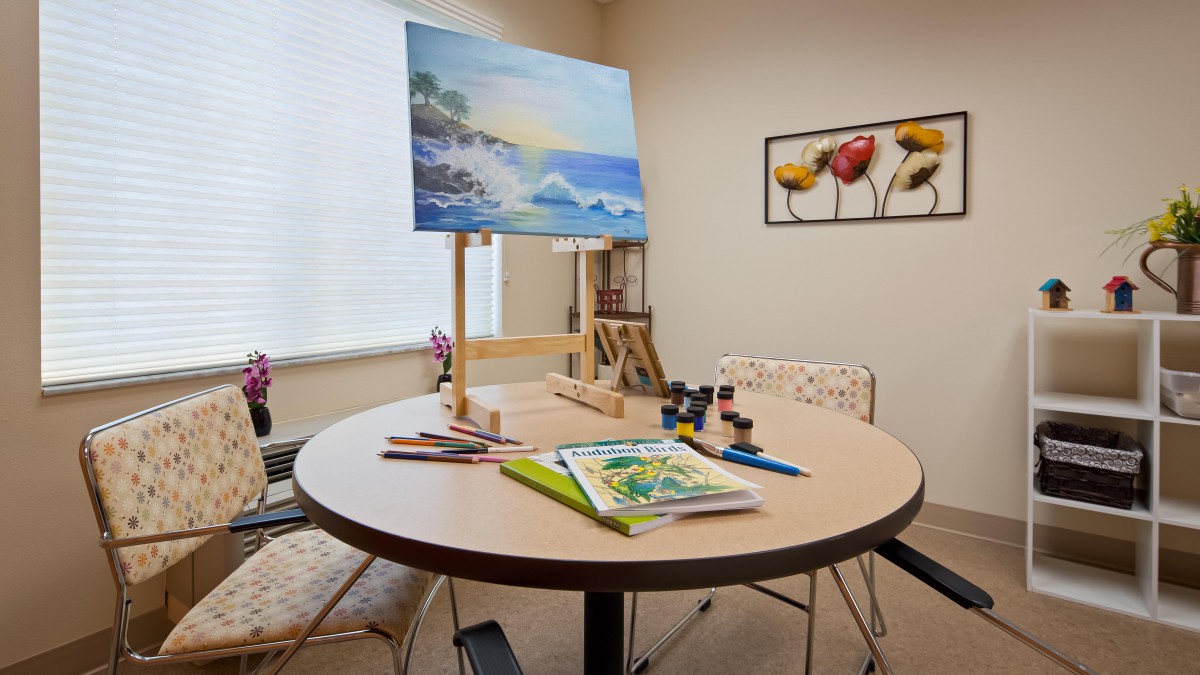 A cozy art studio with a painting on an easel and art supplies on a table.