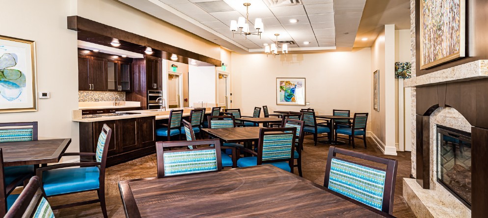 A spacious, modern dining area with neatly arranged tables and chairs, featuring warm lighting and contemporary decor.