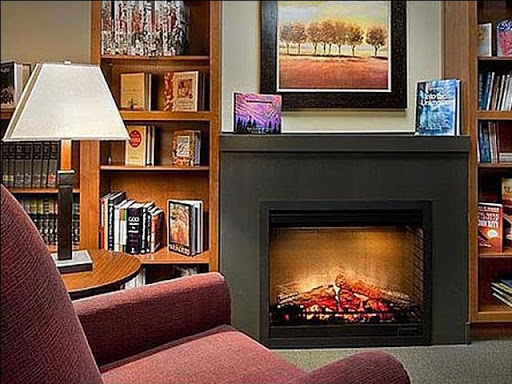A cozy living room featuring a warm fireplace, a bookshelf filled with books, and comfortable seating.