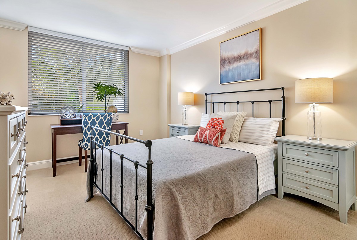 A cozy bedroom with a metal frame bed, patterned chair, and decorative elements.